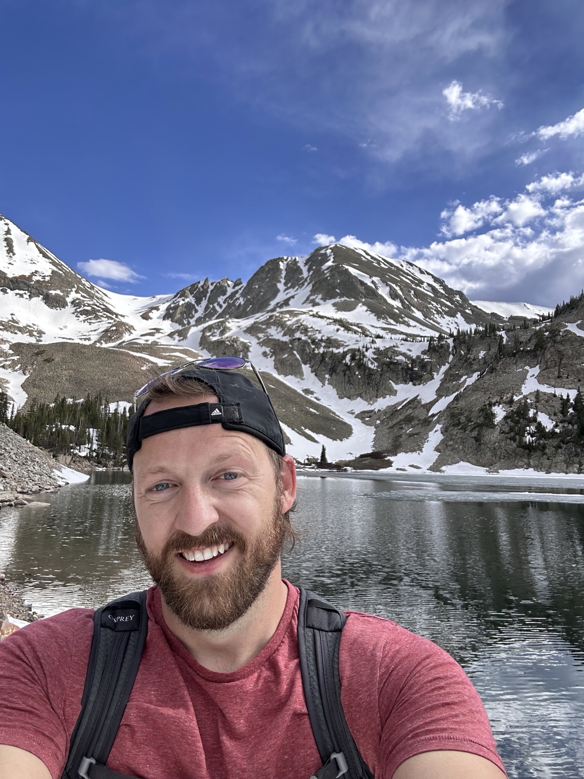 Joe smiling beside a mountain lake